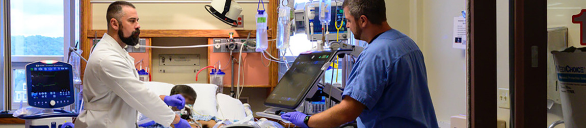 Two healthcare workers looking at a medical device and working with a patient